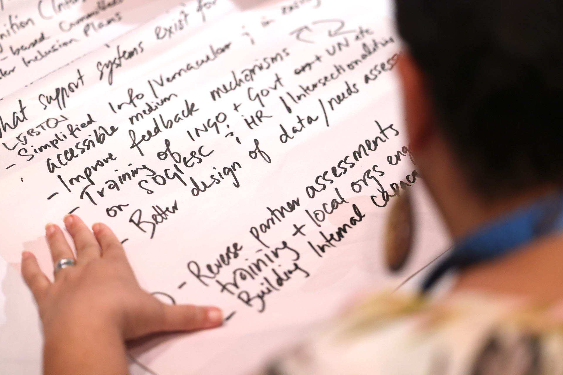 A photo of a woman writing notes on a paper board.