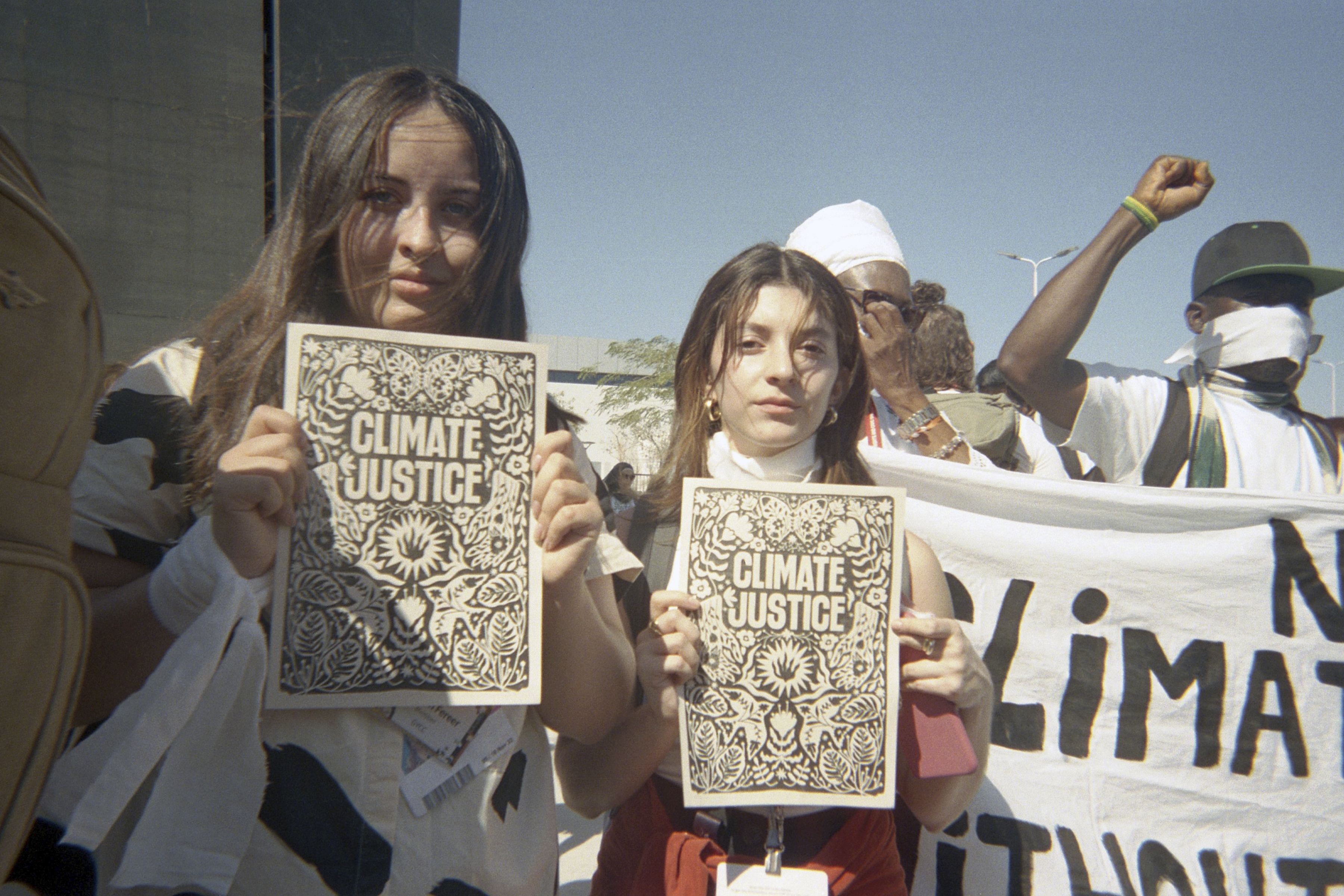 Karin Watson (Chile) and Mariana Chaverri (Costa Rica) with 'Climate Justice' signs at a demonstration