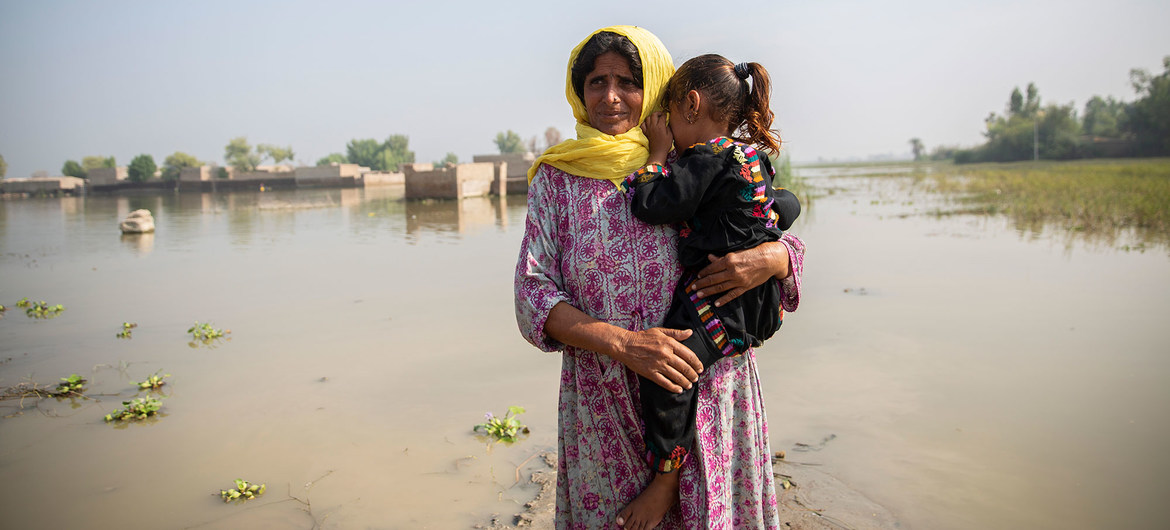 A woman holding a girl near a river.