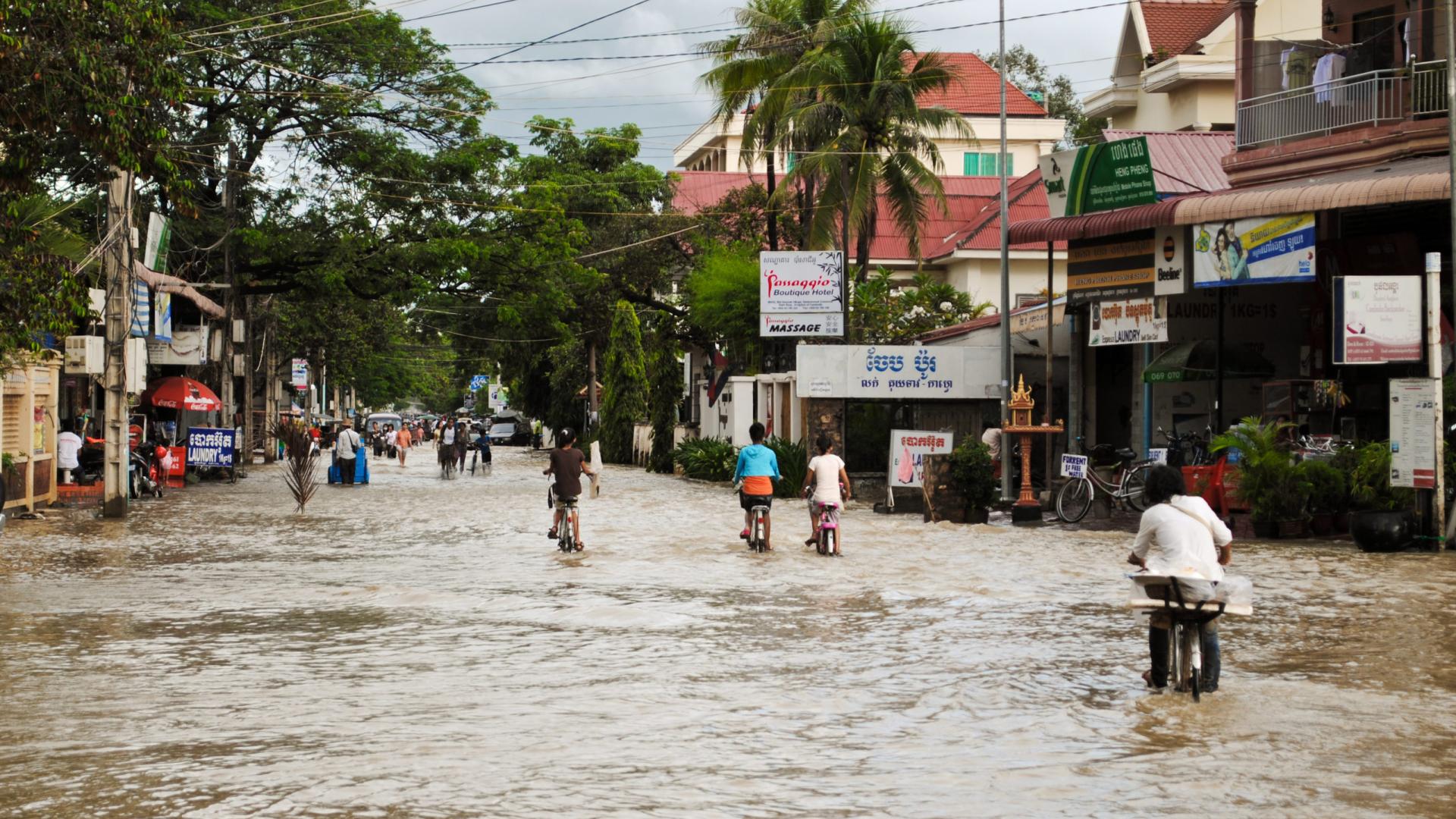 People cycling along a flooded road